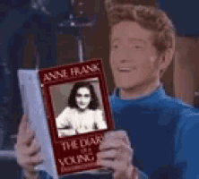 a young man is holding a copy of the diary of anne frank .