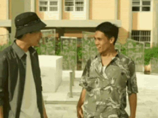 two men are standing next to each other in front of a building .