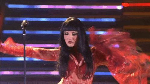 a woman in a red dress is singing into a microphone on a stage