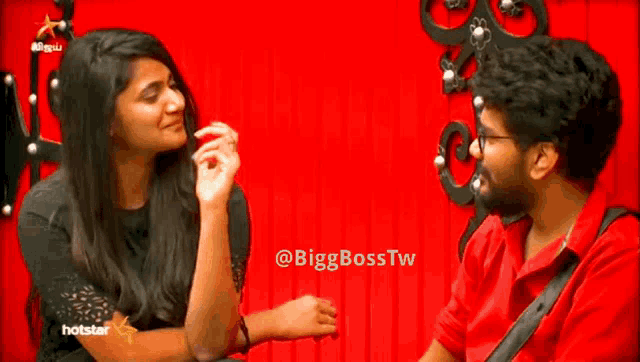 a man and a woman are sitting next to each other on a red background