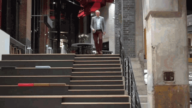 a man in a suit walks up a set of stairs in a building