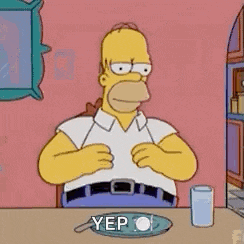 homer simpson is sitting at a table with a plate of food and a cup of water .