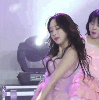 a woman in a pink dress is dancing on a stage in front of a purple background .