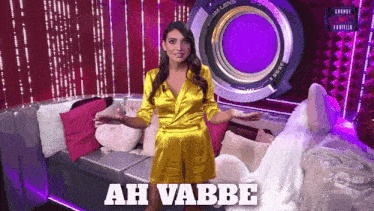 a woman in a yellow dress is standing in front of a camera lens that says ' ah vabbe ' on it