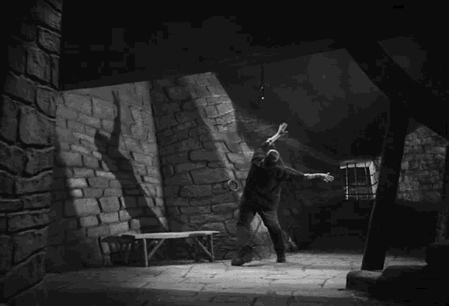 a black and white photo of a man standing in a stone room