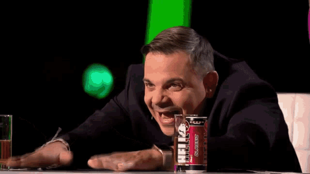 a man sitting at a table with a can of energy drink in front of him that says classic
