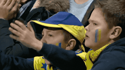a boy wearing a blue and yellow hat and a scarf that says ' nsc ' on it