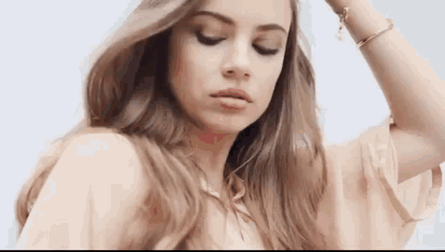 a woman with long hair and a bracelet on her wrist is looking down at the camera .