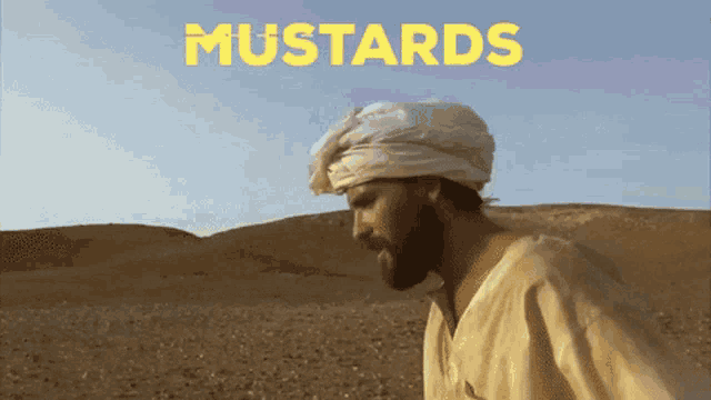 a man in a white turban stands in a desert with the word mustards behind him