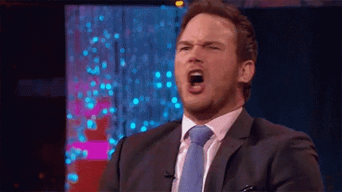 a man in a suit and tie is making a funny face while sitting on a stage .