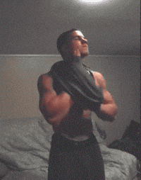 a shirtless man is flexing his muscles in a dark room