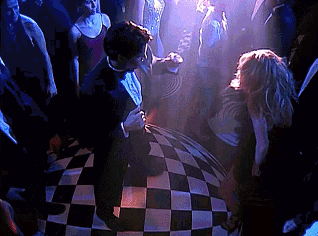a man in a tuxedo is dancing on a checkerboard floor