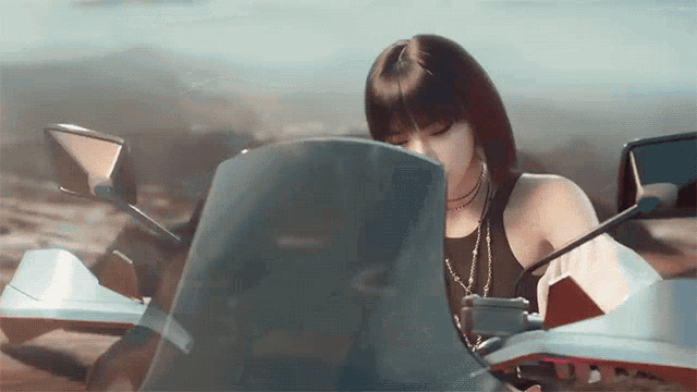 a woman is sitting on a motorcycle in the desert looking at the windshield