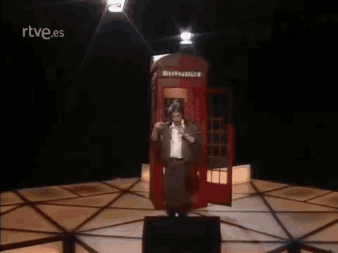 a man is standing in front of a red telephone booth with the word britain on it