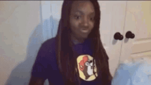 a woman wearing a purple shirt with a picture of a monkey on it is sitting on a bed .