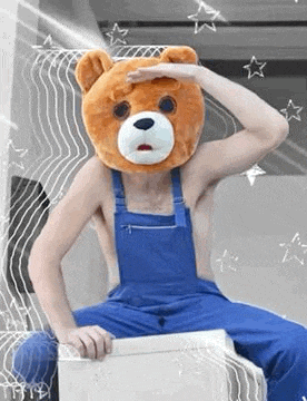 a man with a teddy bear head is sitting on a box .