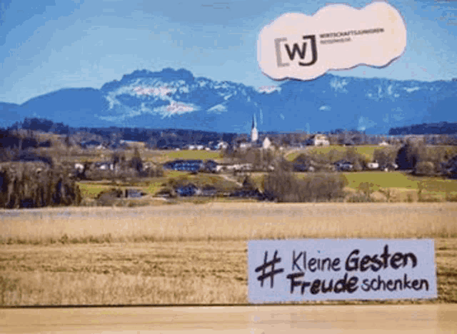 a sign that says kleine gesten freude schenken with a picture of a mountain in the background