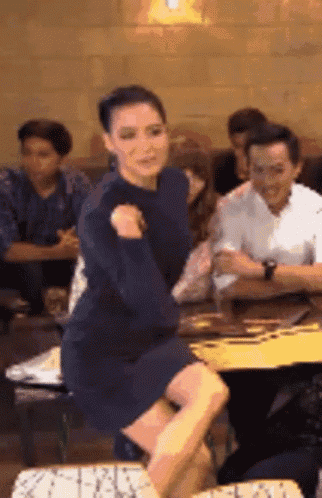 a woman in a blue dress is dancing in front of a crowd