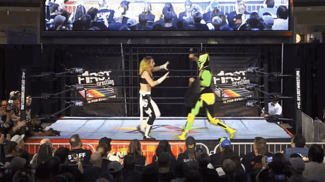 two wrestlers are fighting in front of a crowd at a first wrestling event