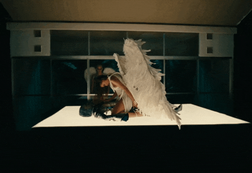 a woman with white wings is laying on a white surface
