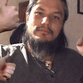 a man with a beard is giving a thumbs up .