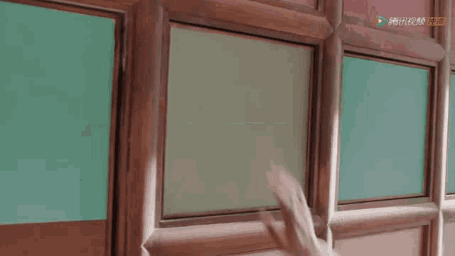 a person 's hand is reaching out to touch a window with a ring on their finger .