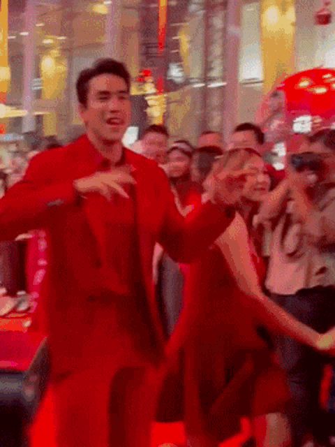a man in a red suit is dancing in front of a crowd
