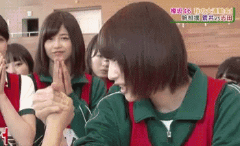 a group of young women are sitting in a room holding hands .