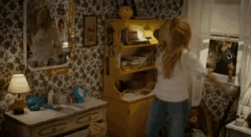 a woman is standing in a room with a dresser and a mirror