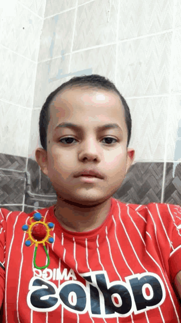 a young boy wearing a red striped shirt that says solbp