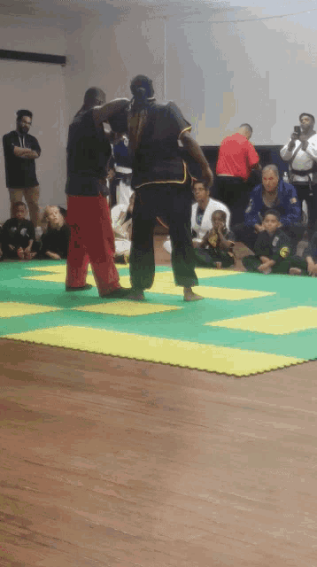 a group of people are sitting on the floor watching a martial arts match