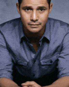 a man in a blue shirt with his hands folded