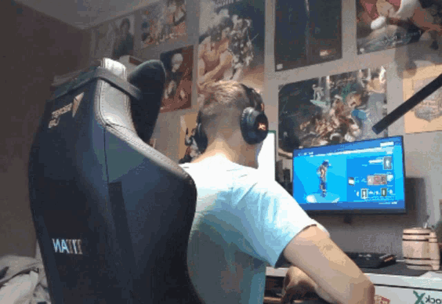 a man wearing headphones sits in a gaming chair that says waiti