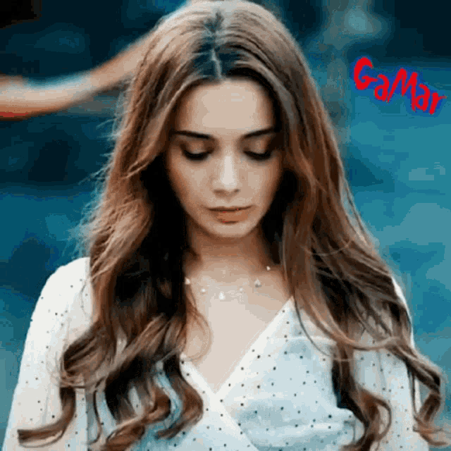 a woman with long hair is wearing a white polka dot top and a necklace
