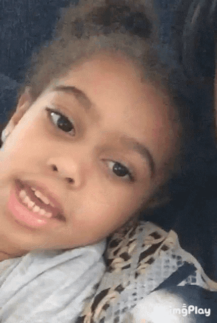 a little girl with curly hair is laying on a couch and smiling .