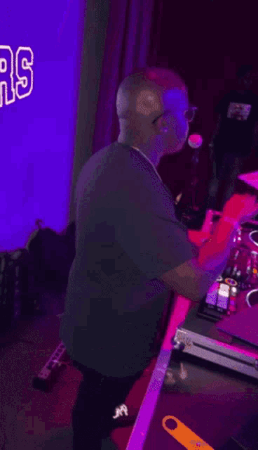 a man is playing a dj mixer in a dark room .