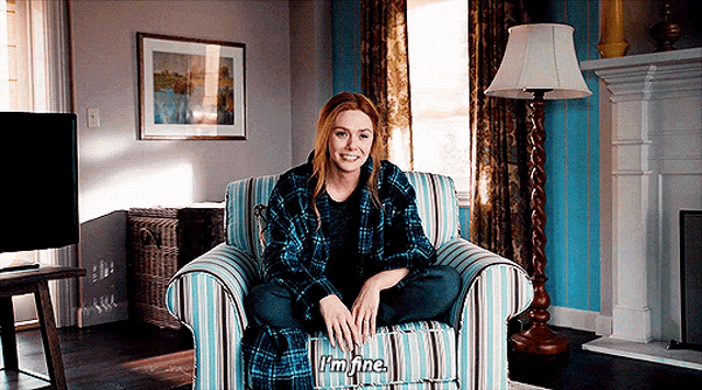 a woman is sitting in a chair with her legs crossed and says i 'm fine .