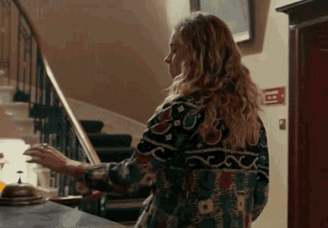a woman in a colorful jacket is standing in front of stairs .