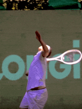 a tennis player is serving a ball in front of a sign that says origin