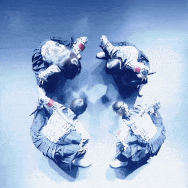 a group of people are dancing in a circle with their arms outstretched