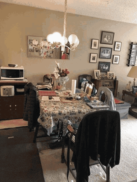 a messy dining room with a table and chairs and a microwave