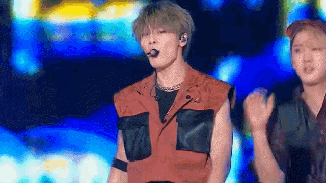 a man in a red vest is standing on a stage in front of a microphone .
