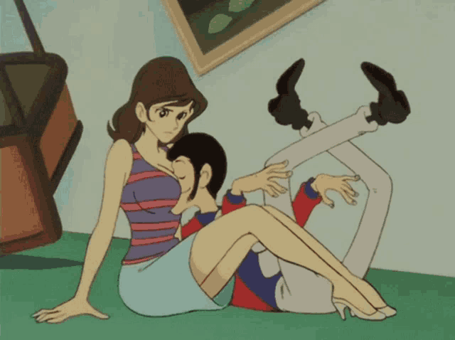 a woman sits on a man 's lap with his legs crossed