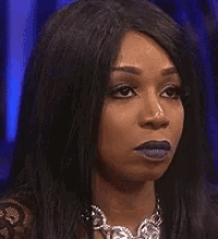a woman wearing purple lipstick and a necklace is making a funny face .