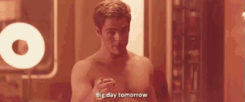 a shirtless man is standing in front of a light and says big day tomorrow