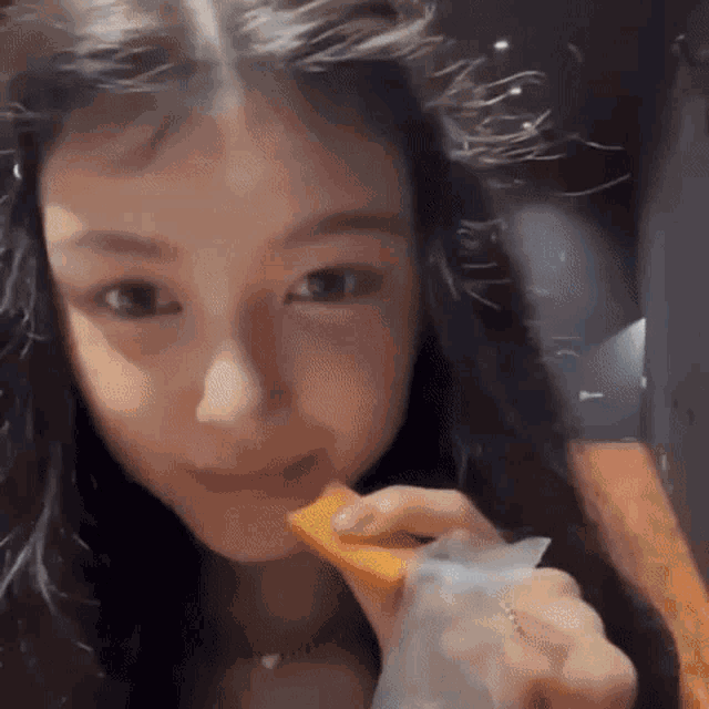 a close up of a woman eating a slice of orange .