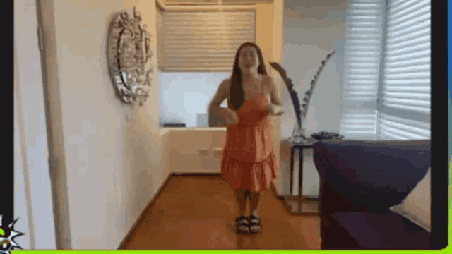 a woman in an orange dress is standing in a hallway