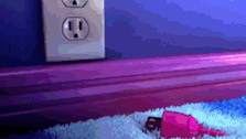 a pink cord is laying on the floor next to a purple wall outlet .