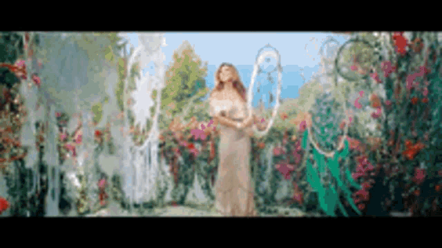 a woman in a white dress is standing in a garden with flowers and holding a dream catcher .
