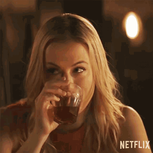 a woman drinking from a glass with netflix on the bottom